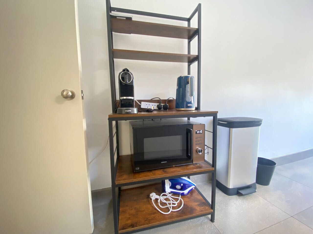 A kitchenette with a microwave, a coffee maker, and a trash bin.
