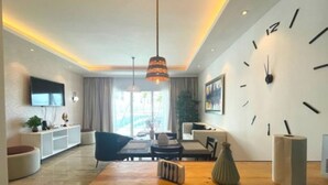 Una sala de estar moderna con una mesa de centro de madera, un reloj de pared grande y un televisor montado en la pared.