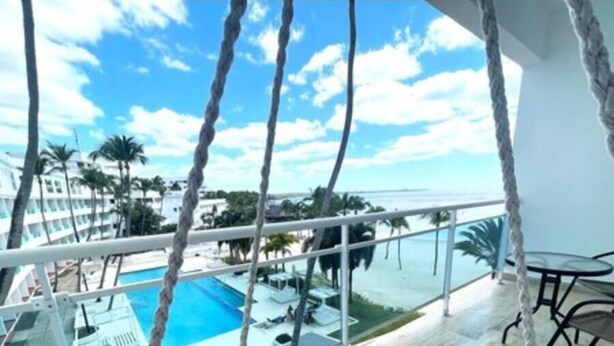 Un balcón con vista a una piscina y palmeras.