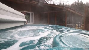 Ein Whirlpool mit Holzterrasse und Blick auf ein Haus im Hintergrund.