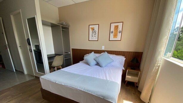 A neatly arranged hotel room with a large bed, a desk, and a wardrobe. - NOBRE HOTEL (Cotia)