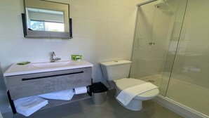 A modern bathroom with a glass shower enclosure, a toilet, and a sink with a mirror above it. - NOBRE HOTEL (Cotia)