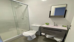 A modern bathroom with a glass shower enclosure, a toilet, and a vanity with a sink and mirror. - NOBRE HOTEL (Cotia)