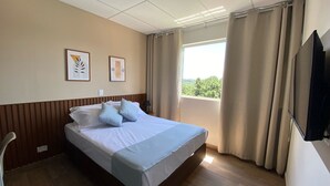 A hotel room with a bed, a TV, a window with curtains, and two framed pictures on the wall. - NOBRE HOTEL (Cotia)