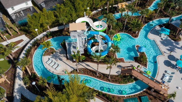 A water park with multiple pools, slides, and a wooden deck.
