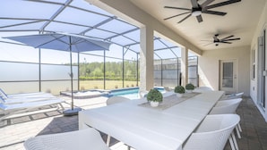 Une terrasse extérieure couverte avec une piscine, des meubles blancs et des ventilateurs de plafond.