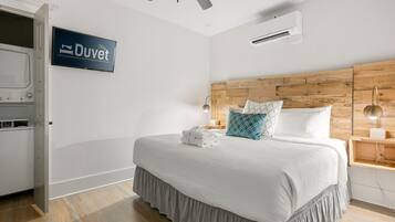 A neatly made bed with a white duvet, a wooden headboard, and a sign that reads "Stay Duvet".
