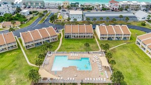 Et resort med en central pool, flere bygninger og udsigt over havet.