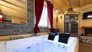 A modern spa room with a large bathtub, wooden walls, a stone accent wall, and a fireplace. - C_AL RANCH WELLNESS CORTINA, LAKE CADORE, DOLOMITES (PIEVE DI CADORE)
