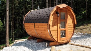 A wooden cabin with a sloped roof, a door, and a window, surrounded by trees and gravel. - C_AL RANCH WELLNESS CORTINA, LAKE CADORE, DOLOMITES (PIEVE DI CADORE)