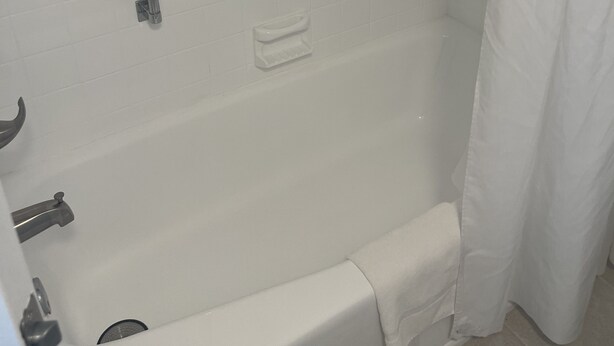 A bathroom with a white bathtub, a grab bar, and a shower curtain. - ALL BRAND-NEW Waterfront room-Heated Pool, Tiki Bar, Gym (Sarasota)
