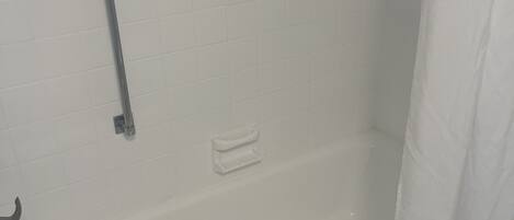 Ein Badezimmer mit einer weißen Badewanne, einer Haltestange und einer Duschvorhang.