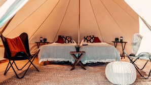 Eine gemütliche Zelthütte mit zwei Betten, einem kleinen Tisch und Sitzbereichen.