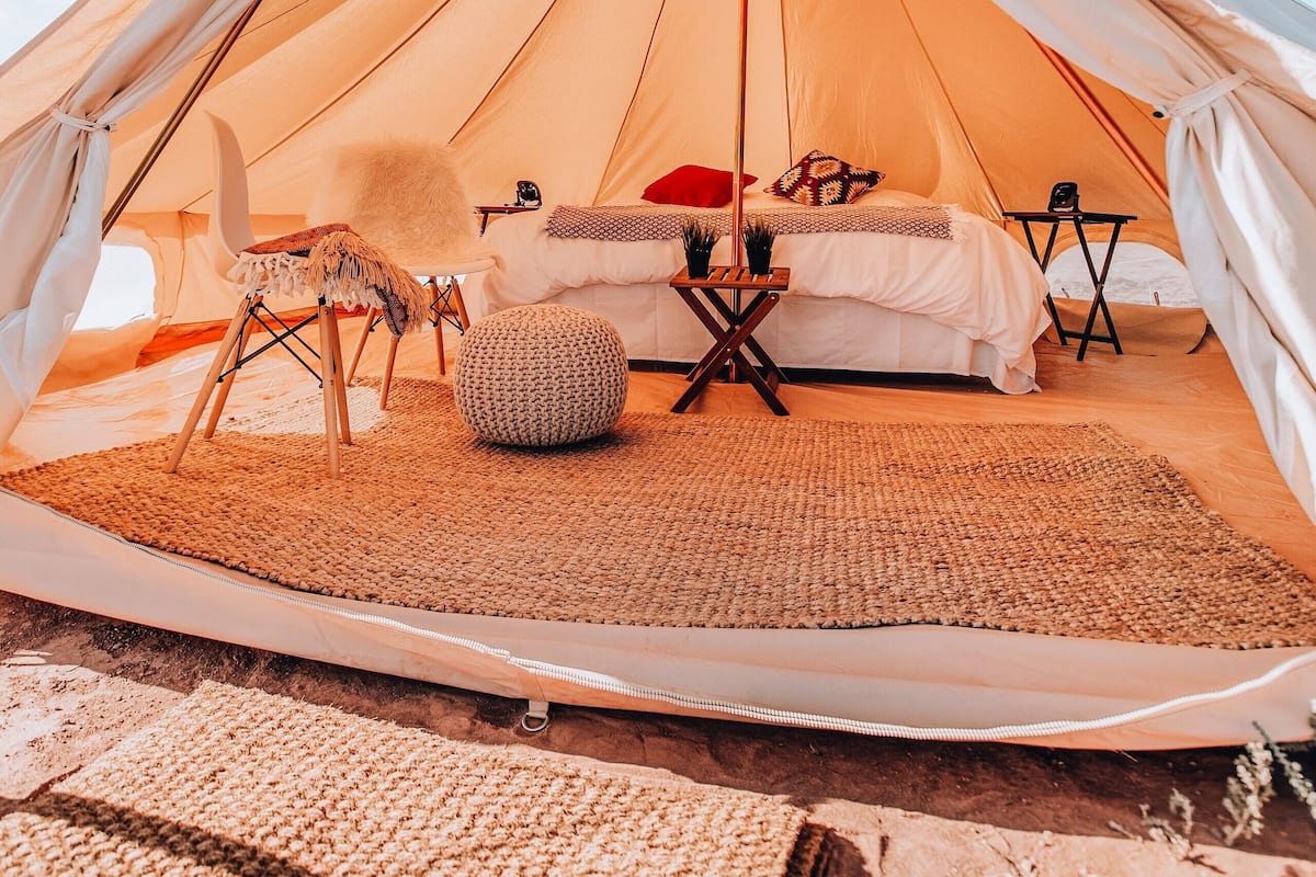 A tent with a bed, pillows, a chair, and a small table.