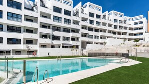 Un hotel moderno de varios pisos con piscina, mobiliario exterior y una escalera que conduce a los pisos superiores.
