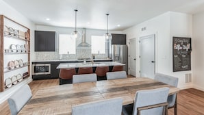 Una cocina moderna con una isla central, luces colgantes y una pared de pizarra.