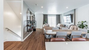 Una sala de estar moderna con comedor, una escalera y una estantería.