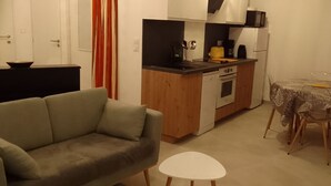A compact living space with a kitchenette, a dining area with a table and chairs, and a sofa. - Maison à 50 m de la mer (Saint-Jacut-de-la-Mer)