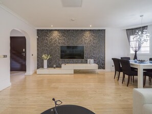 Relax in this stylish living space with a flat-screen TV, dining area, and large window.