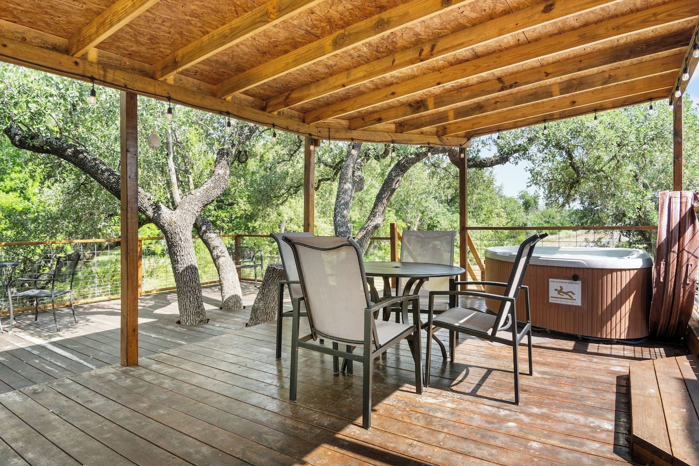 An outdoor wooden deck with a table and chairs, surrounded by trees.