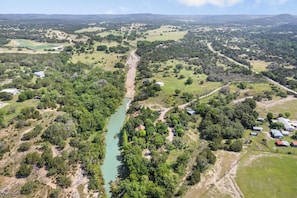 A rural landscape with a river, scattered buildings, and green fields. - Stronghold Tipi | Creek Access & Hot Tub & Fishing (Bandera)