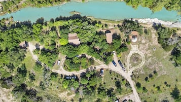 An aerial view of a property with a lake, multiple buildings, and a winding road.