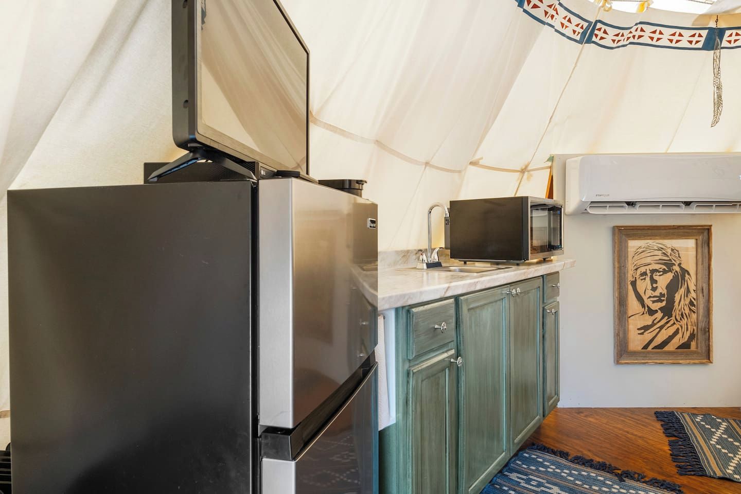 A compact kitchen with a refrigerator, microwave, and sink.