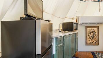 A compact kitchen with a refrigerator, microwave, and sink.