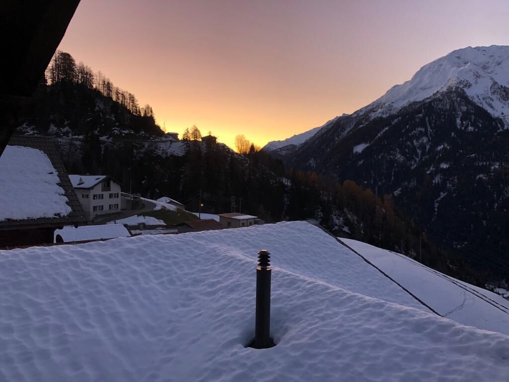 A snowy mountain landscape with a building in the foreground.