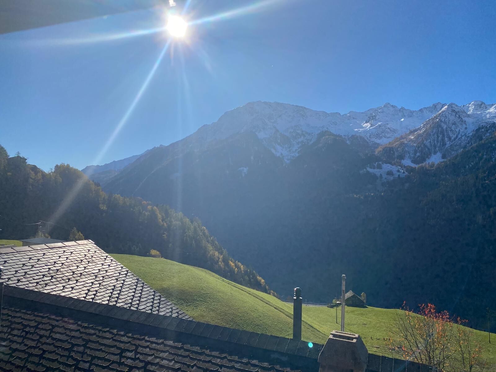 Paisaje montañoso con cielo despejado y un edificio con techo inclinado.
