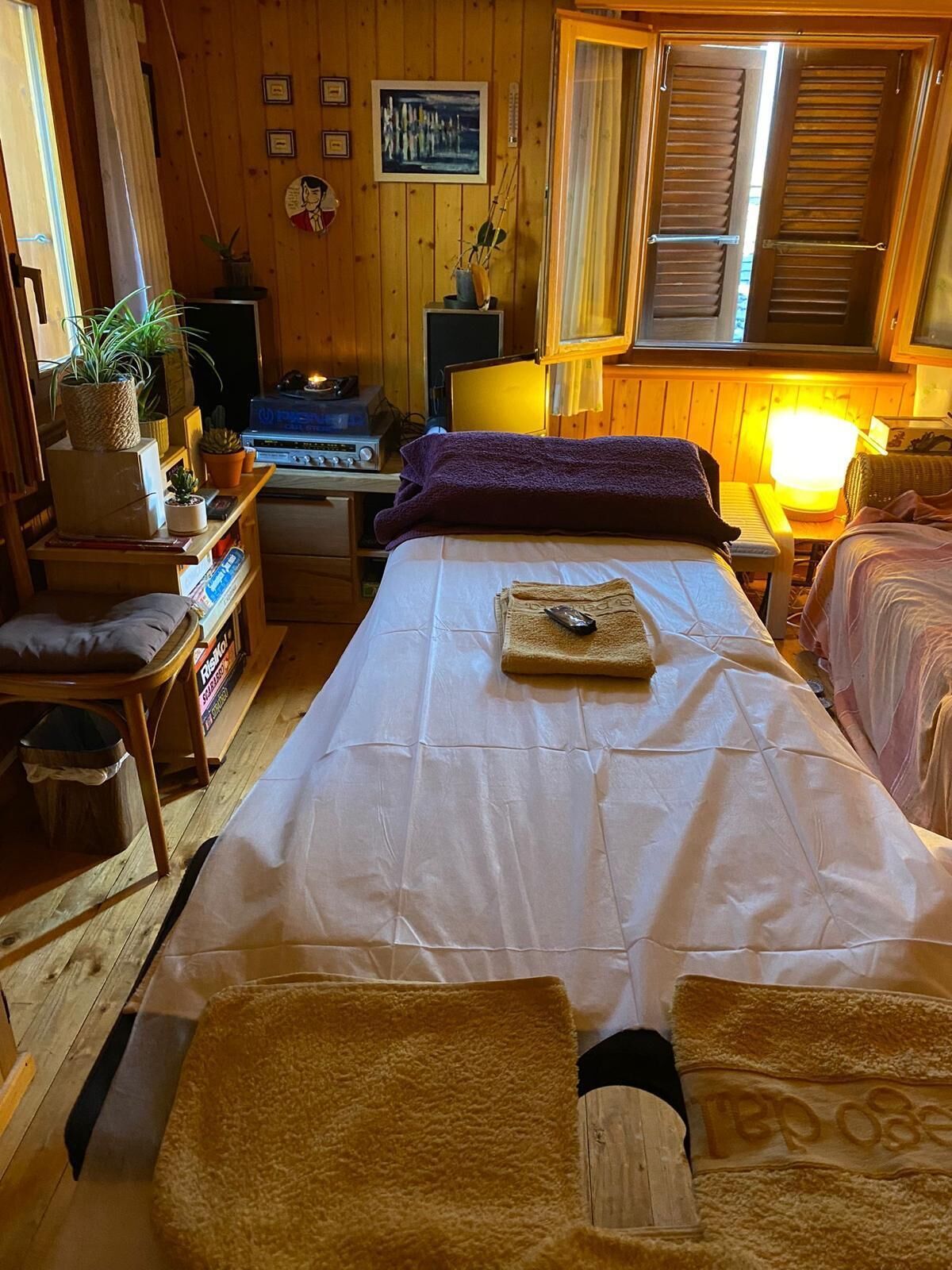 A cozy room with a bed, a desk, a chair, and a small table.