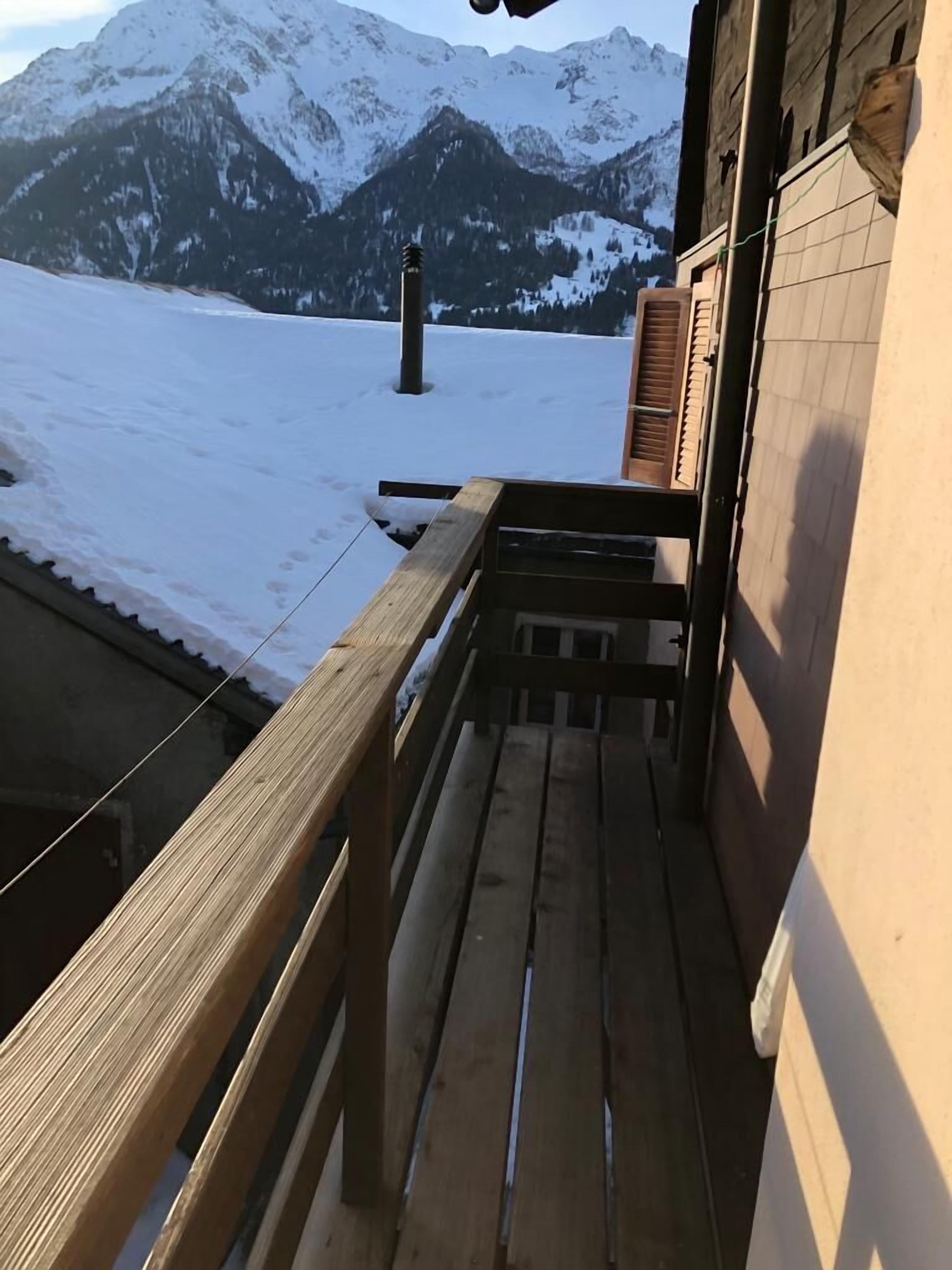 A wooden balcony with a view of snow-covered mountains.