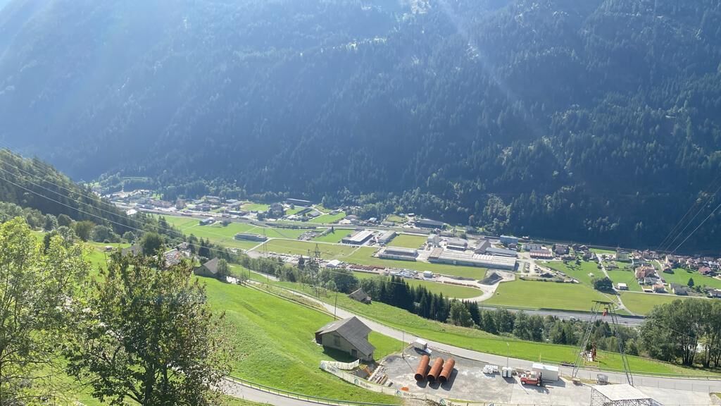 Ett kuperat landskap med en by som har grönskande fält, byggnader och en väg.