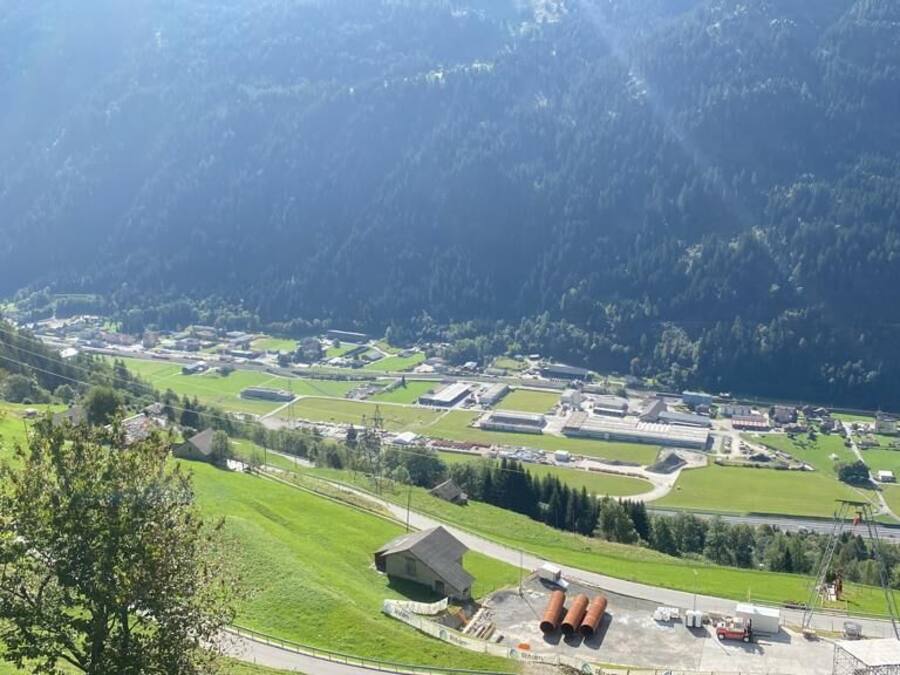 Un paysage montagneux avec un village caractérisé par des champs verdoyants, des bâtiments et une route.