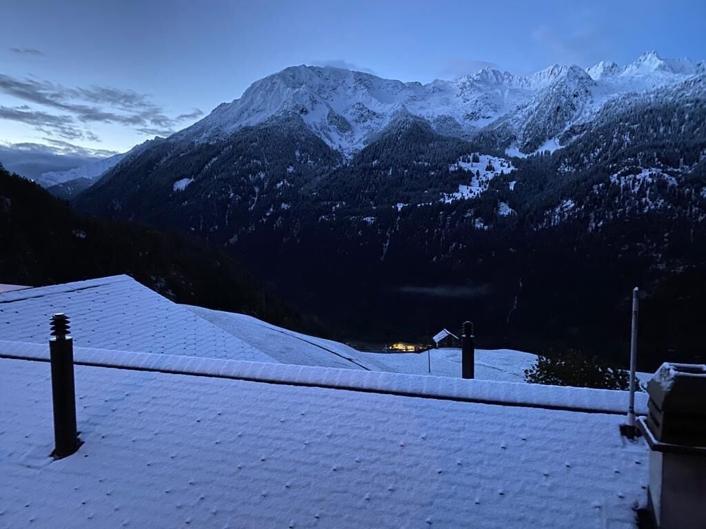 Un paisaje montañoso nevado con una casa a lo lejos.