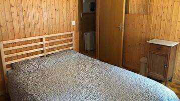 Une chambre à coucher avec une tête de lit en bois, un lit recouvert d’une couvre-lit à motifs, une armoire et un petit meuble.