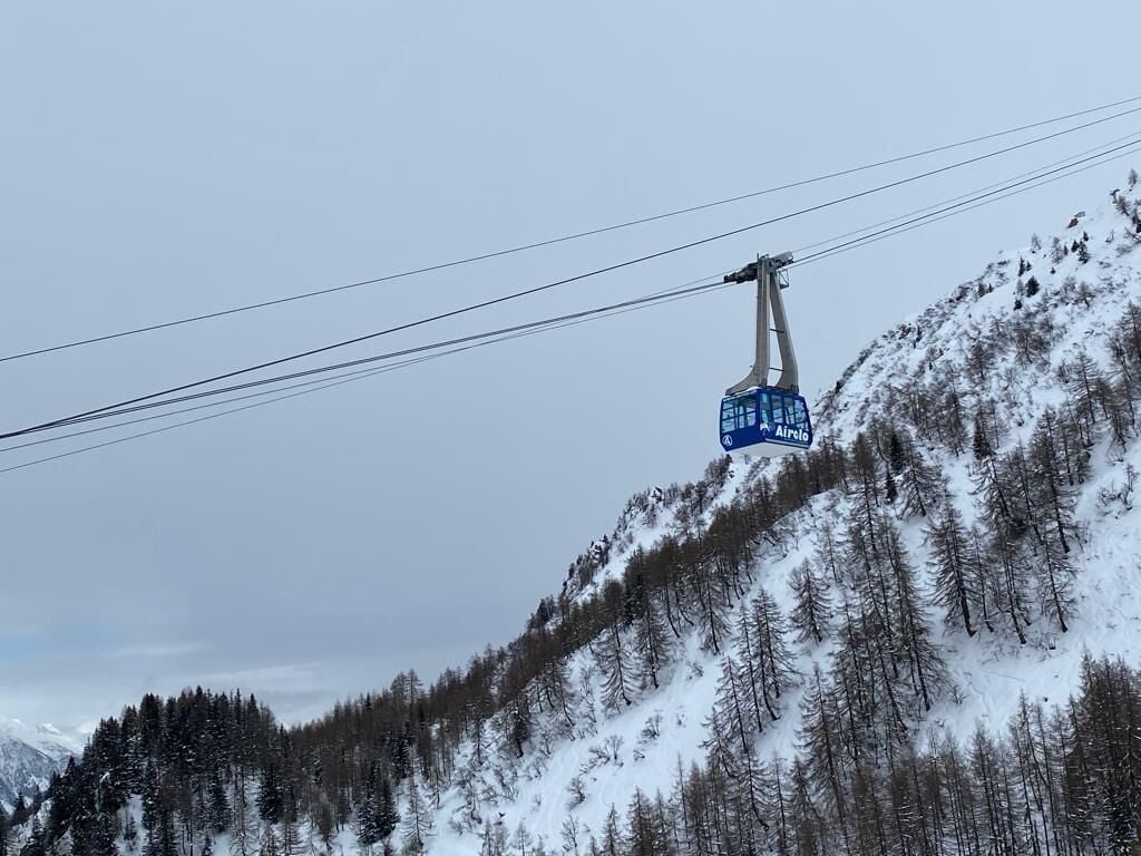 Une télécabine portant une enseigne indiquant « Airelo » est suspendue au-dessus d’une montagne enneigée.