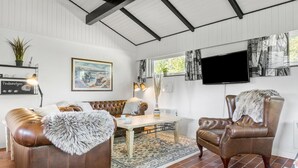 A living room with a brown leather sofa, a brown leather armchair, a coffee table, and a television mounted on the wall. - Cozy home in Sydals with WiFi (Sydals)