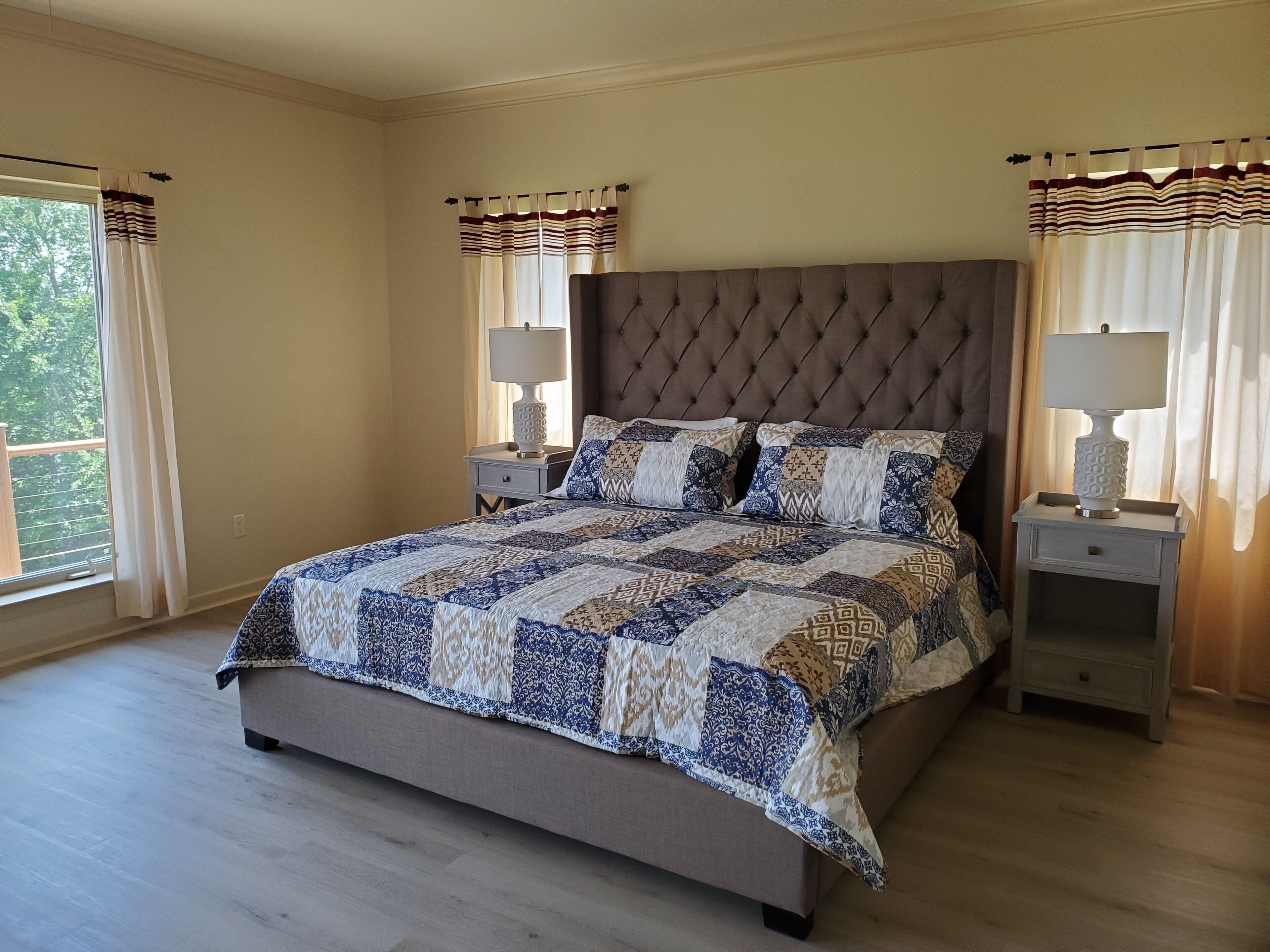 A bedroom with a large bed, two bedside tables, and curtains.