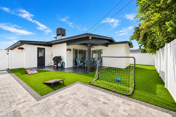 A modern house with a patio, a barbecue area, and a small soccer goal.