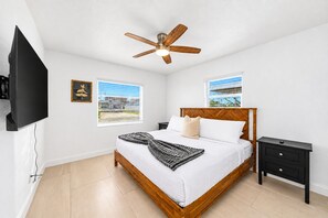 A bedroom with a bed, a nightstand, a ceiling fan, and a TV.
