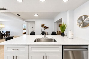 A modern kitchen with a central island, stainless steel appliances, and a dining area with a table and chairs.