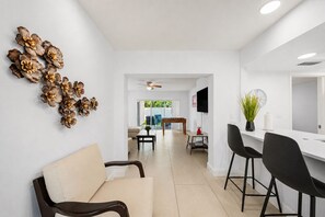 Una sala de estar moderna con un sofá, sillas, una mesa de centro y decoración en las paredes.