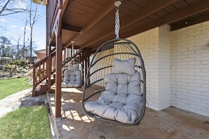 A hanging chair with a cushioned seat and backrest, suspended from a ceiling with a chain. - Marietta GEM 4-bedroom/3 bed - pet friendly -flexible monthly stays  (Marietta)