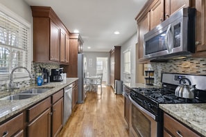 A kitchen with wooden cabinets, granite countertops, a stainless steel microwave, and a gas stove. - Marietta GEM 4-bedroom/3 bed - pet friendly -flexible monthly stays  (Marietta)