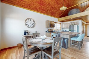 Une cuisine spacieuse avec un îlot central, un plafond en bois et une grande horloge au mur.