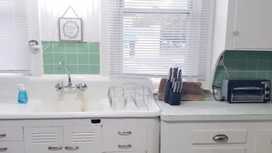 A kitchen with a white sink, a toaster, and a window with blinds. - B-town King and Queen (Bloomington)