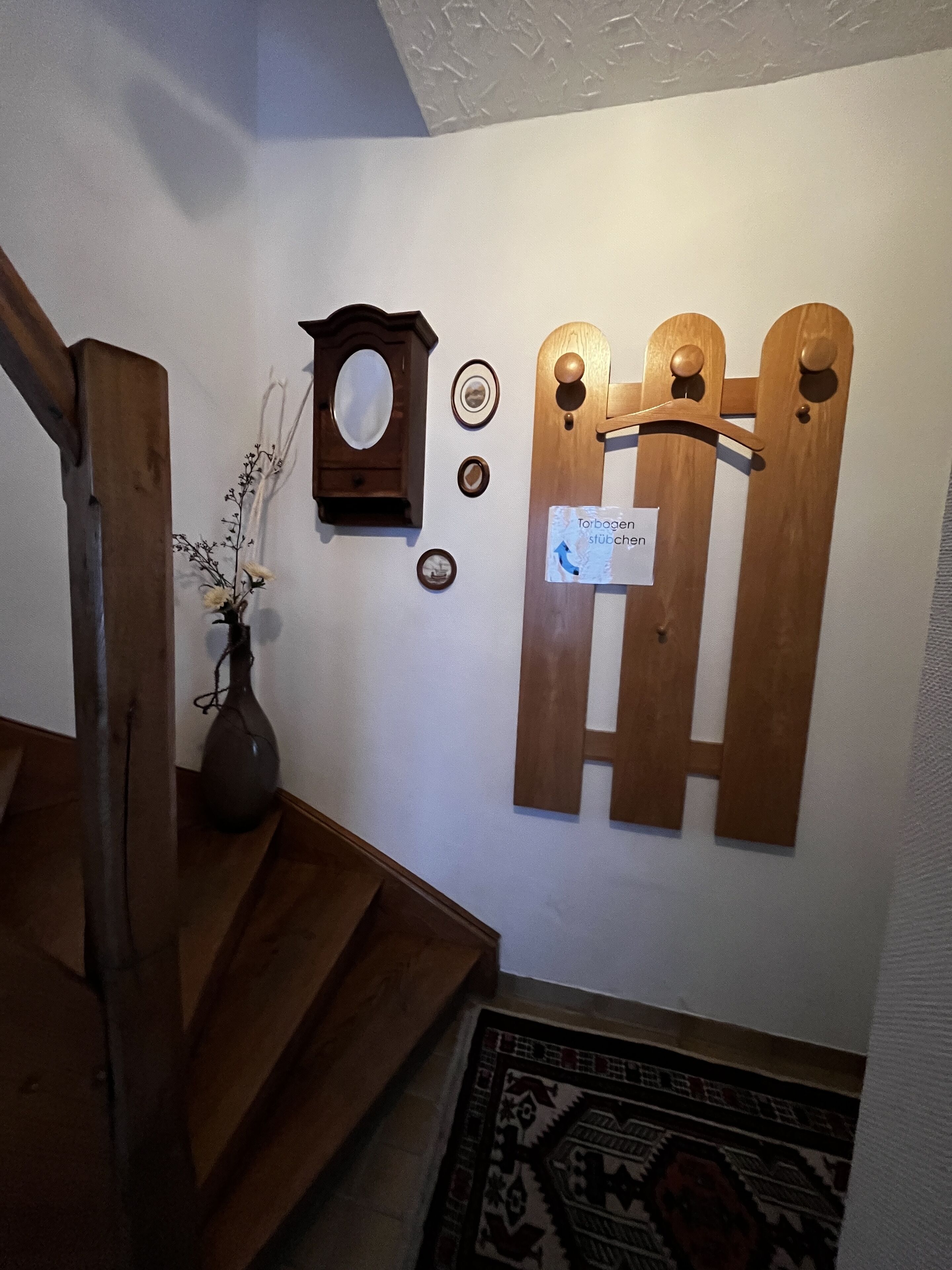 A wooden staircase with a vase of flowers on the landing.
