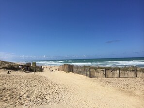 A sandy beach with a wooden fence and a clear blue sky.