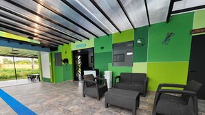 A covered outdoor seating area with wicker furniture, a small table, and a refrigerator. - Quaint Villa in Villavicencio. Connect with nature without compromising comfort (Villavicencio)